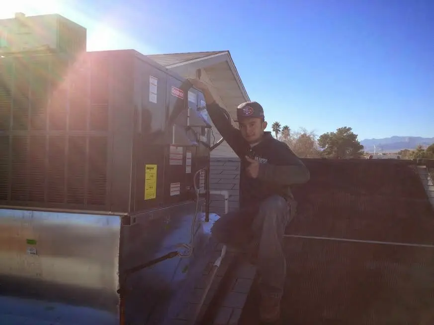 HVAC technician performing AC Tune-Up on a rooftop unit in The Meadows